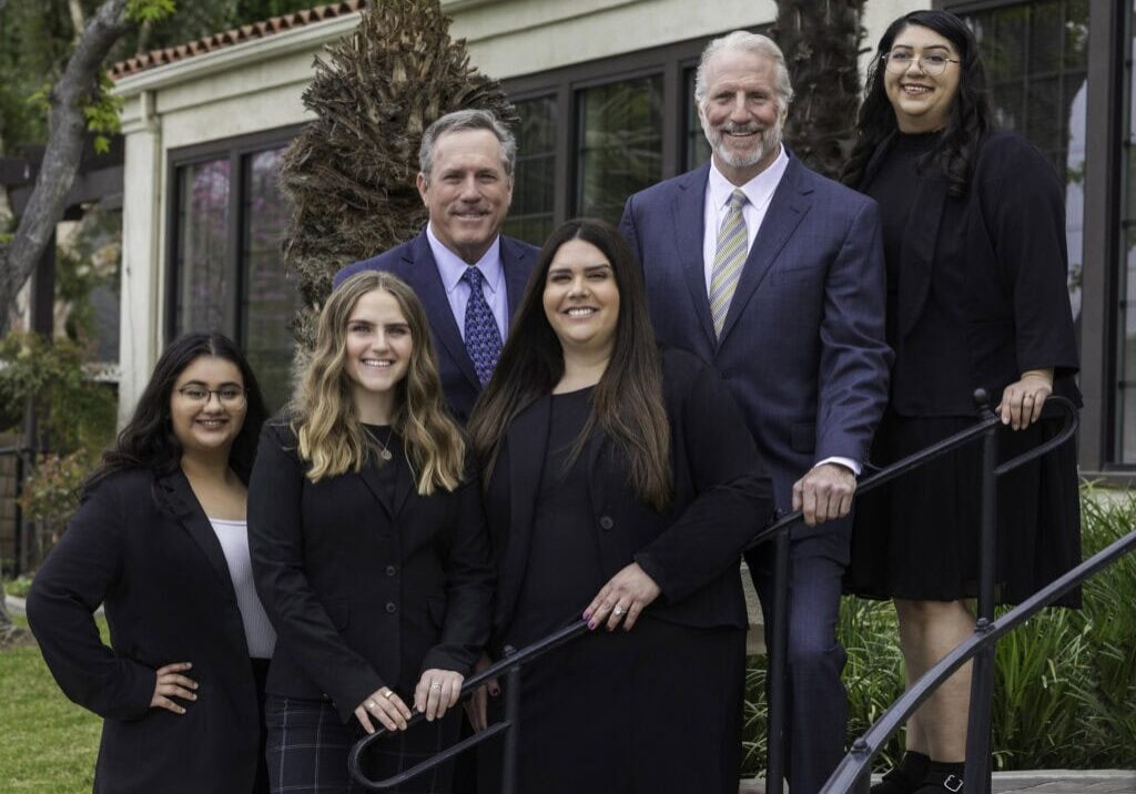 Donahoo & Associates attorneys and staff posing for a team photo on the stairs in front of their legal office.